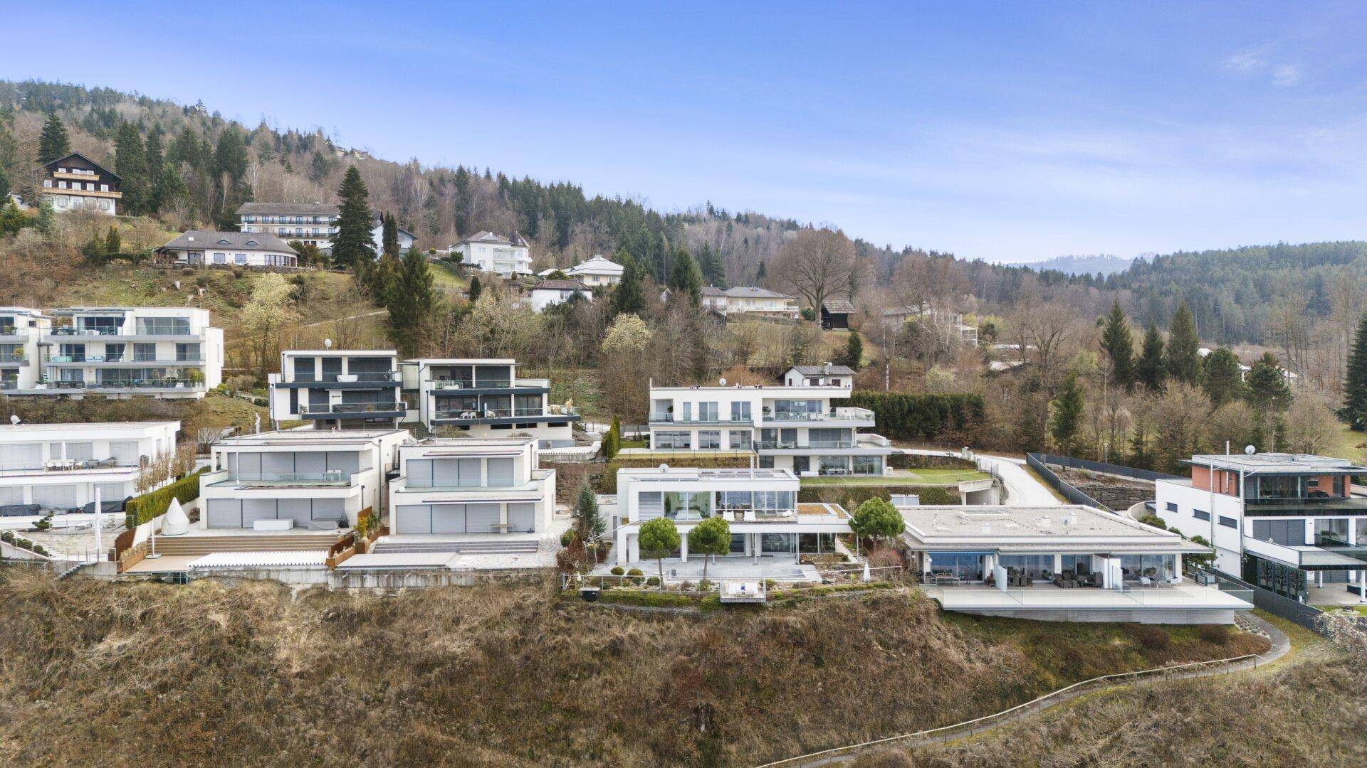 Panoramablick auf die moderne Wohnsiedlung am Hang mit Seeblick und viel Grün.