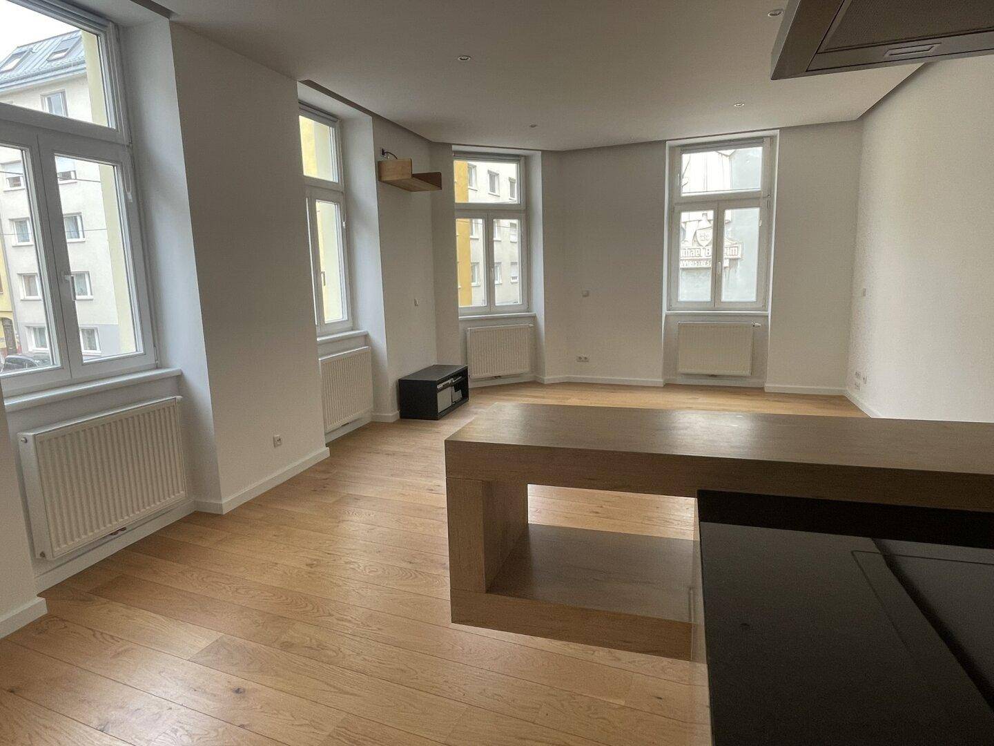 Heller Wohnbereich mit vielen Fenstern und elegantem Holzparkettboden.