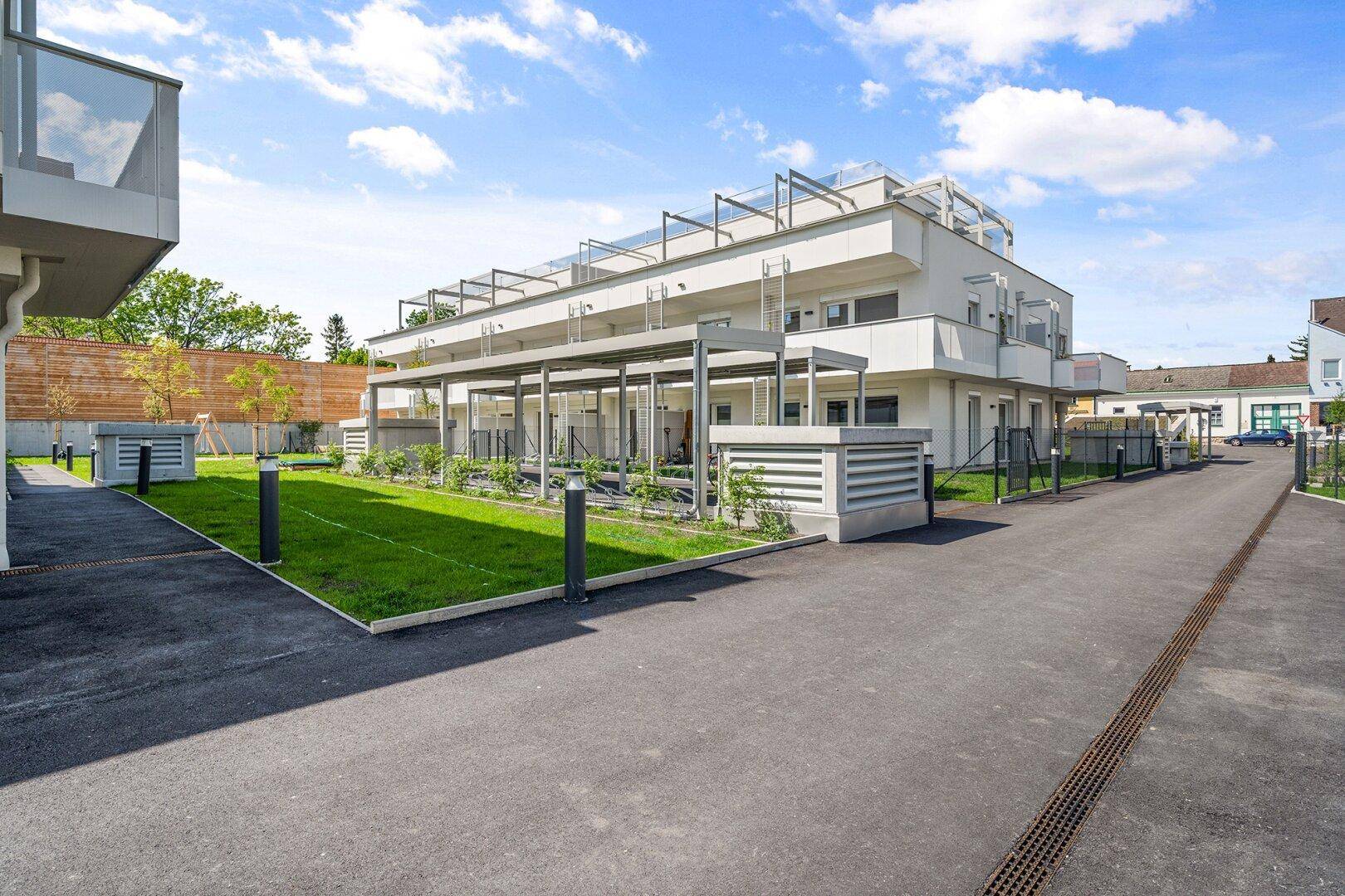Moderne Wohngebäude mit klaren Linien und gepflegten Außenanlagen bei sonnigem Wetter.