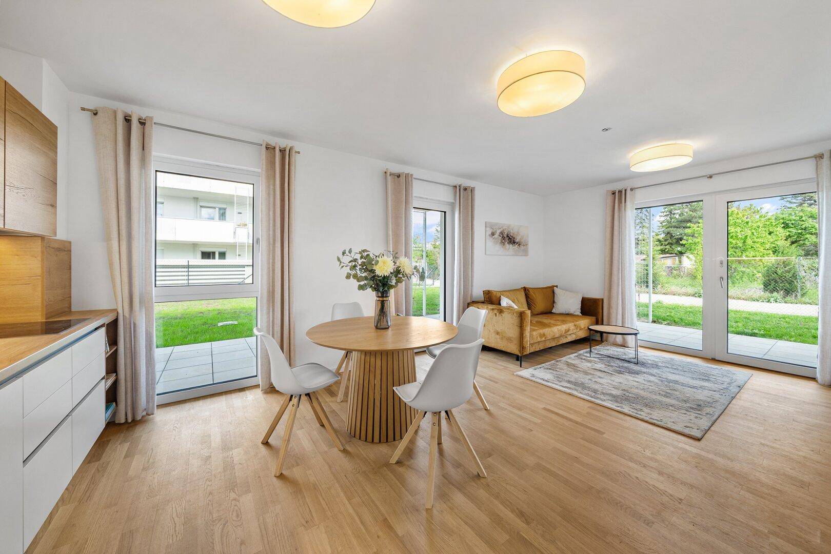 Offener Wohn-Essbereich mit moderner Küche, Holzboden und Zugang zum Garten.