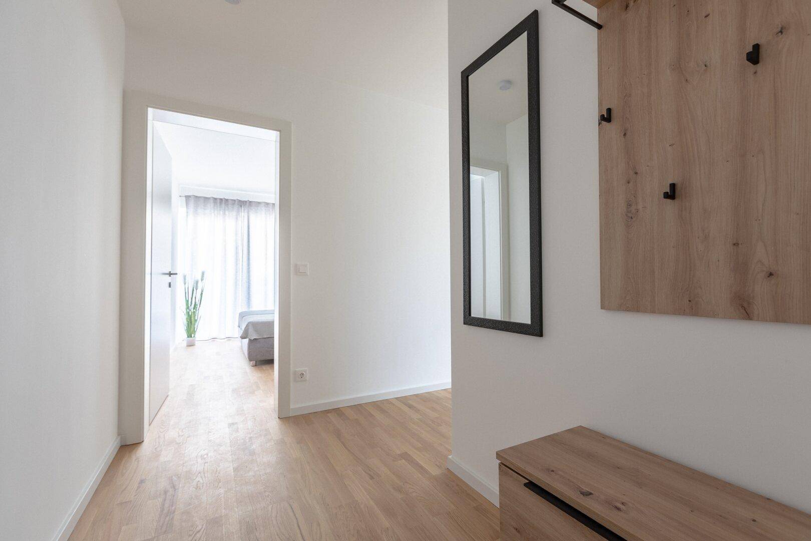 Eingangsbereich mit Garderobe, Spiegel und Holzboden, hell und einladend.