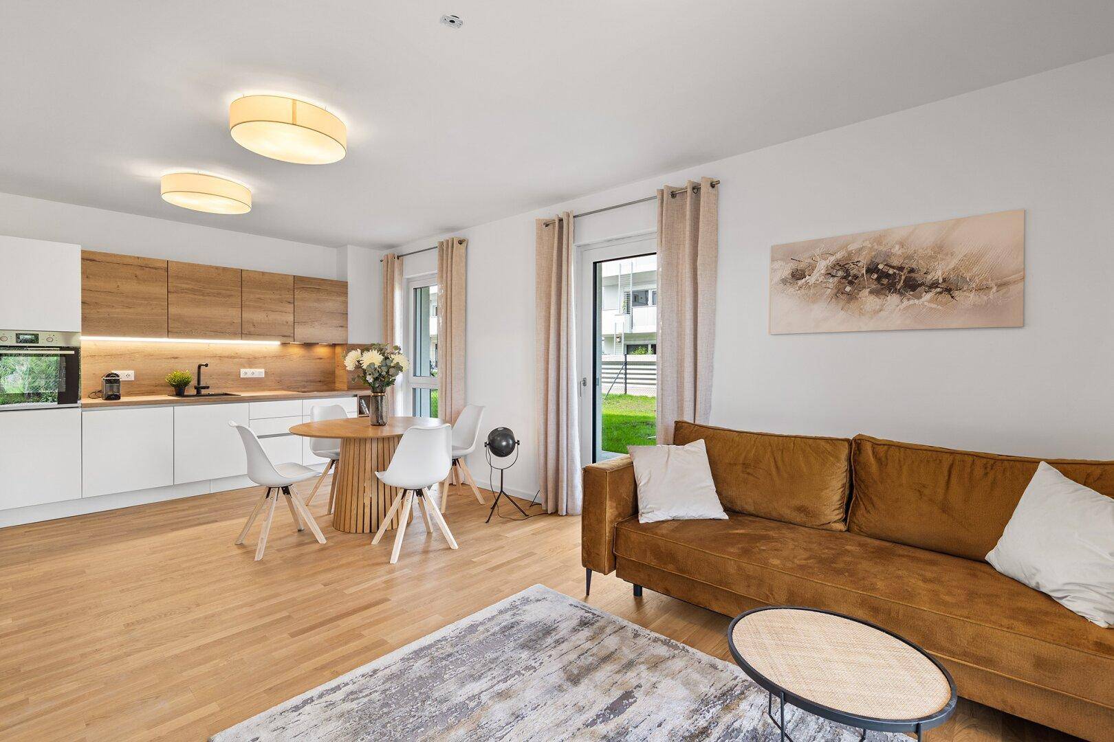 Geräumiger Wohn-Essbereich mit offener Küche, bequemer Couch und Gartenzugang.