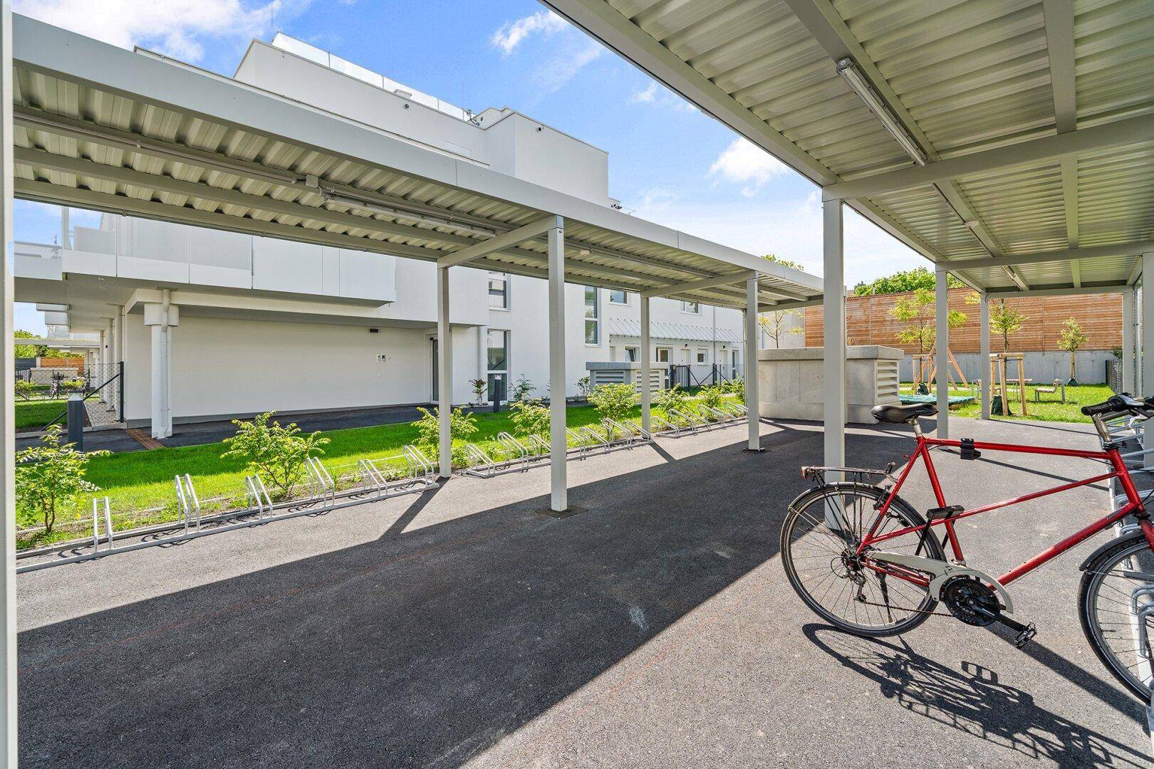 Überdachte Fahrradabstellplätze und Carports in der modernen Wohnanlage.