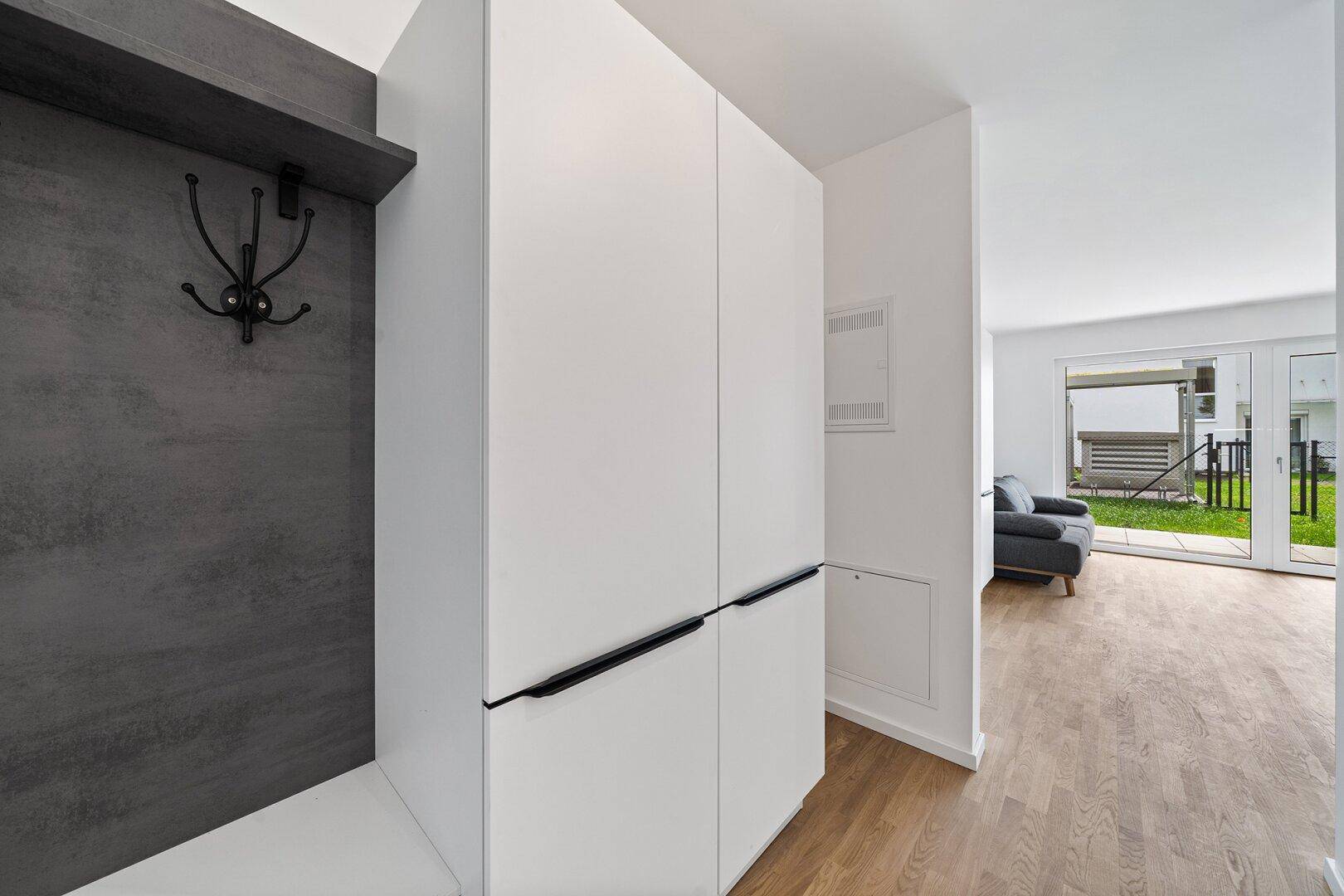 Heller Eingangsbereich mit Garderobe und praktischen Einbauschränken, führt zum Wohnbereich mit Gartenzugang.