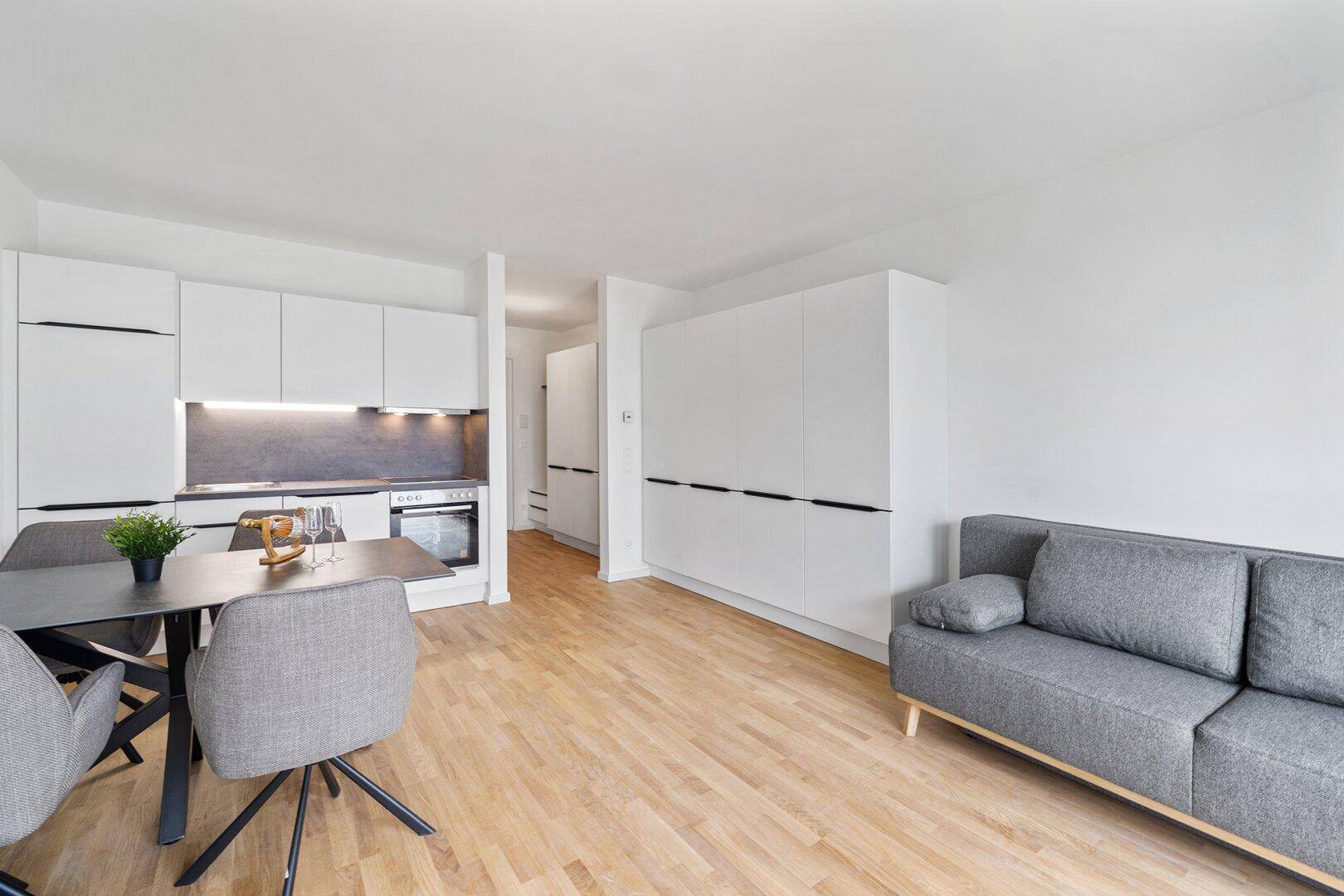 Geräumiger offener Wohnbereich mit integrierter Küche, Essplatz und Sofa, ideal für modernes Wohnen.