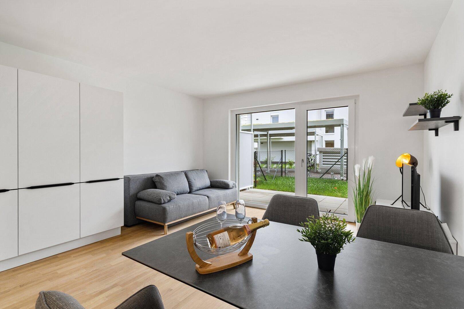 Gemütlicher Wohn- und Essbereich mit Zugang zum Garten, ausgestattet mit modernem Sofa und Esstisch.