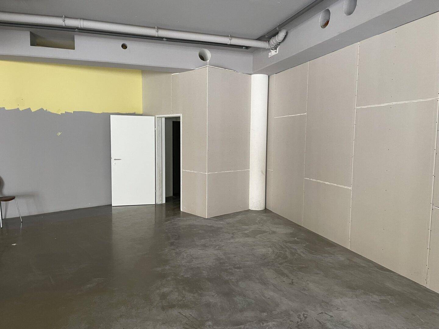 Geräumiger Innenbereich mit Trockenbauwänden und sichtbaren Rohren an der Decke, bereit für den Ausbau.