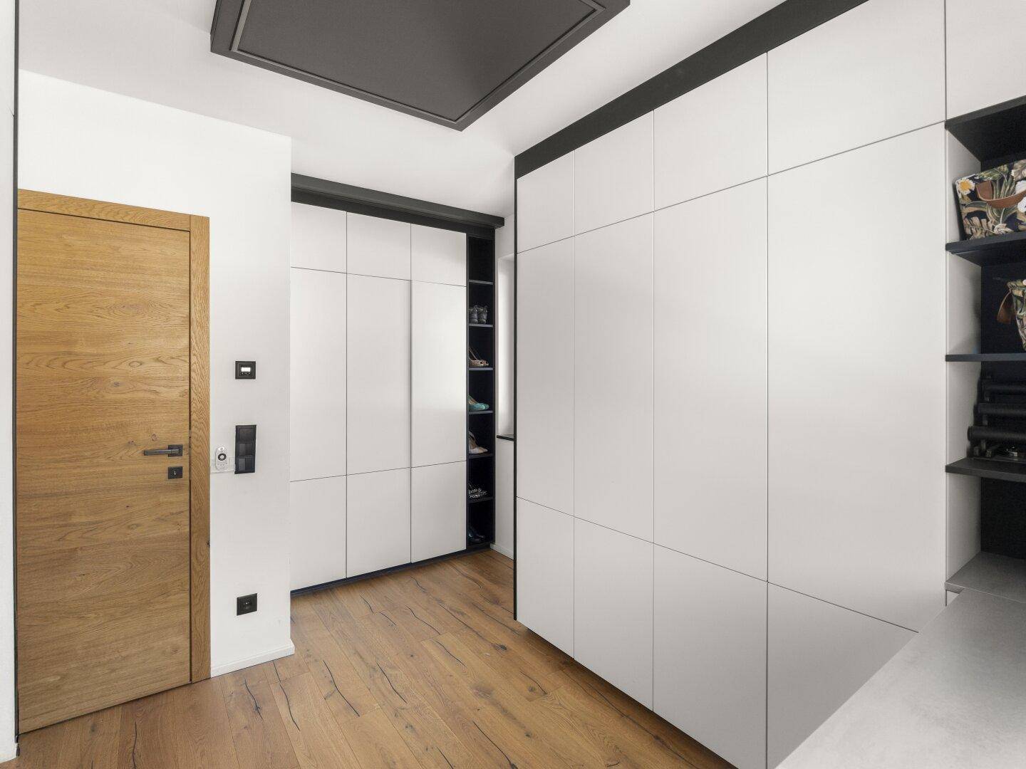 Heller Flur mit Holztür und modernen Einbauschränken für zusätzlichen Stauraum.