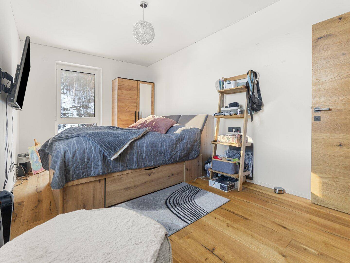 Gemütliches Schlafzimmer mit Holzbett, Holzboden und moderner Einrichtung.