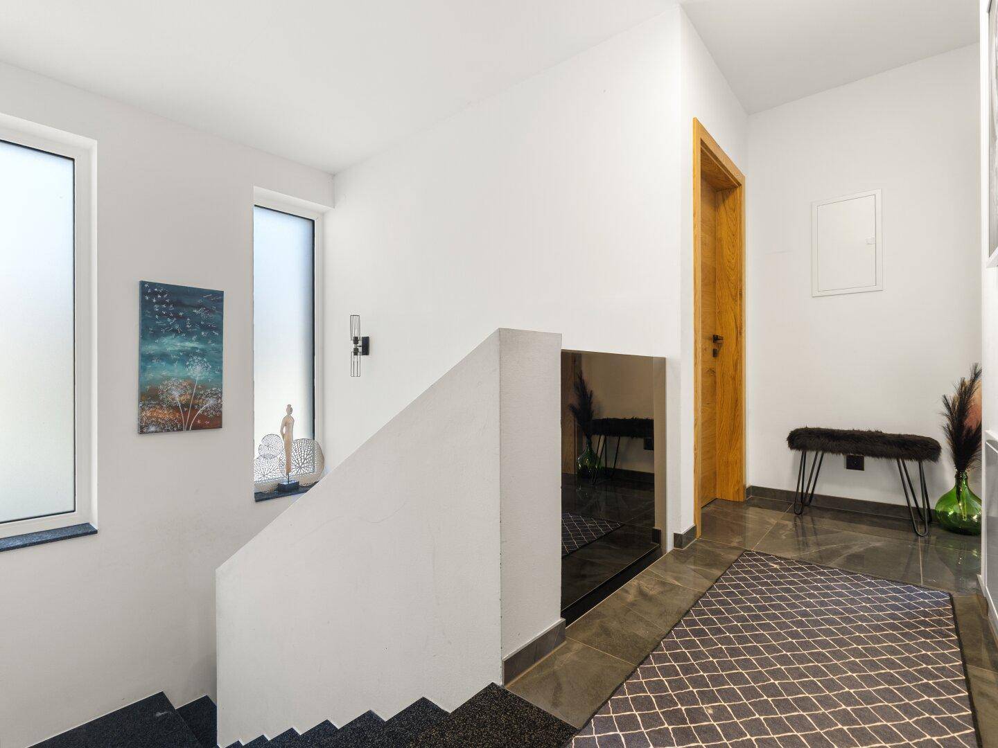 Heller Treppenbereich mit weiß gestrichenen Wänden und natürlichem Lichteinfall.