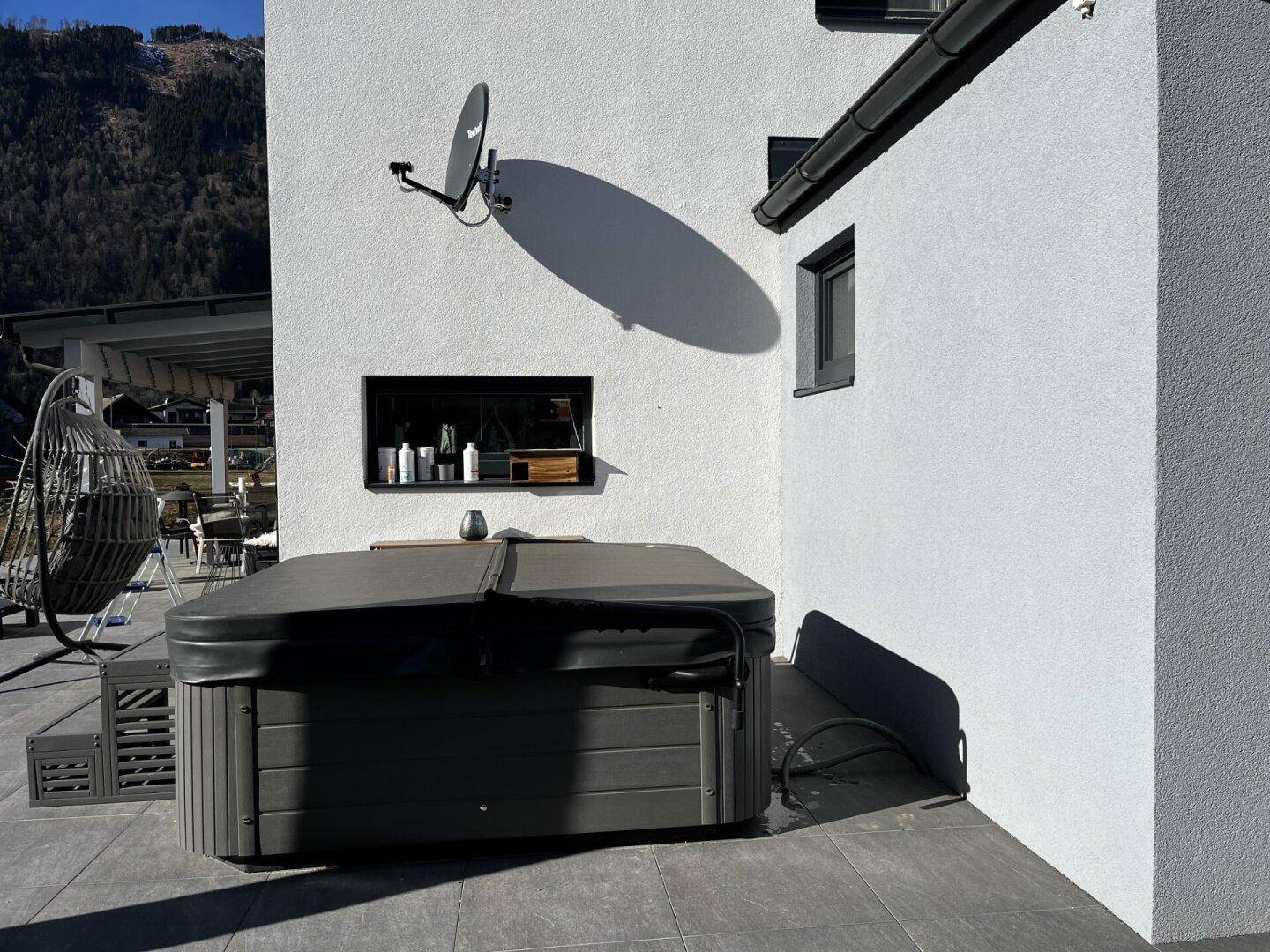 Außenbereich mit Whirlpool auf der Terrasse und Blick auf die umliegenden Berge.