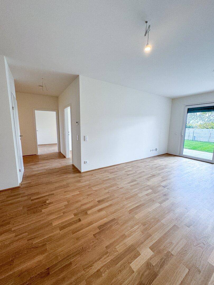 Geräumiger, heller Wohnbereich mit Parkettboden und direktem Zugang zur Terrasse und zum Garten.