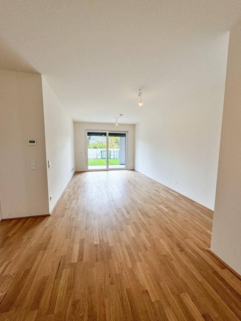 Heller Wohnbereich mit Holzboden und großer Schiebetür, die viel Tageslicht hereinlässt.