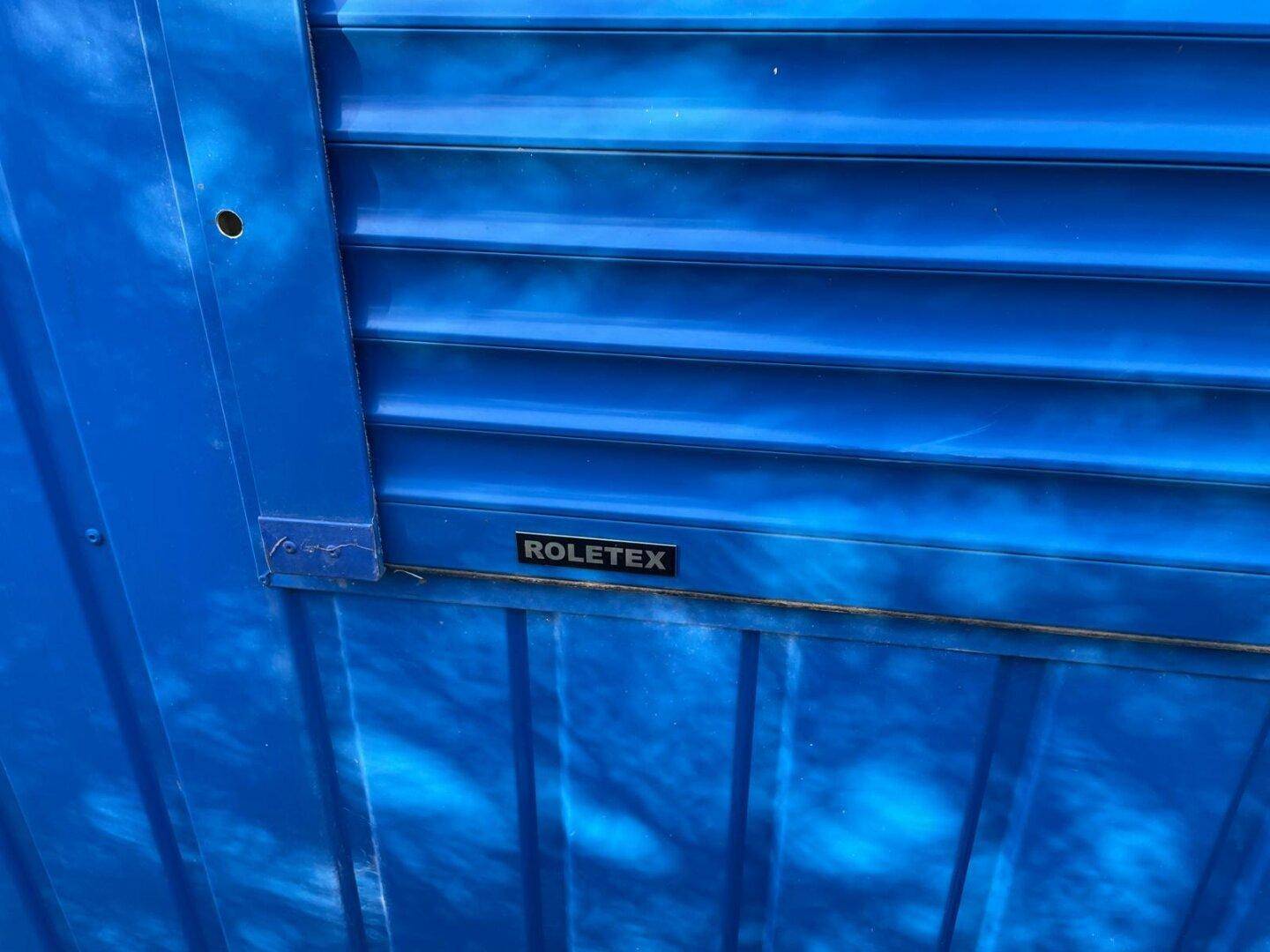 Nahaufnahme eines blauen Rollladens am Containergebäude, der die Struktur und Farbe deutlich zeigt.