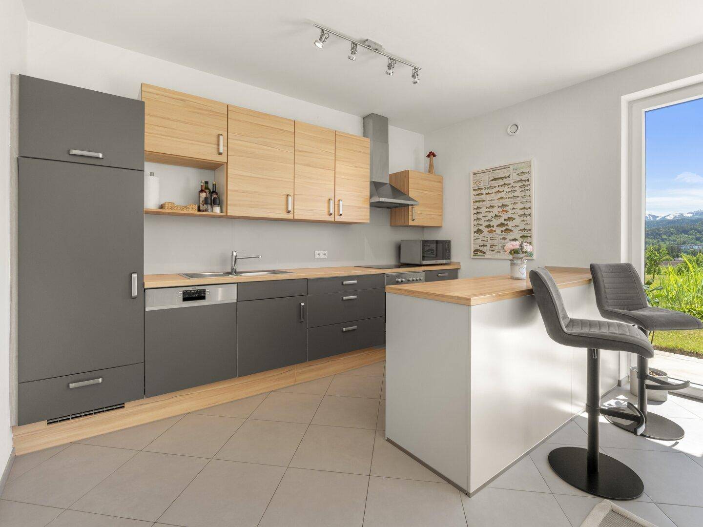 Moderne Einbauküche mit grauen und holzfarbenen Fronten, Bar und Fenster.