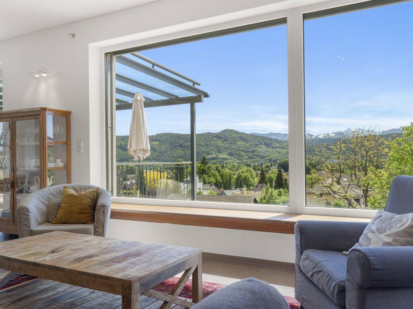 Wohnzimmer mit bodentiefen Fenstern und weitem Blick auf die Berge und Landschaft.