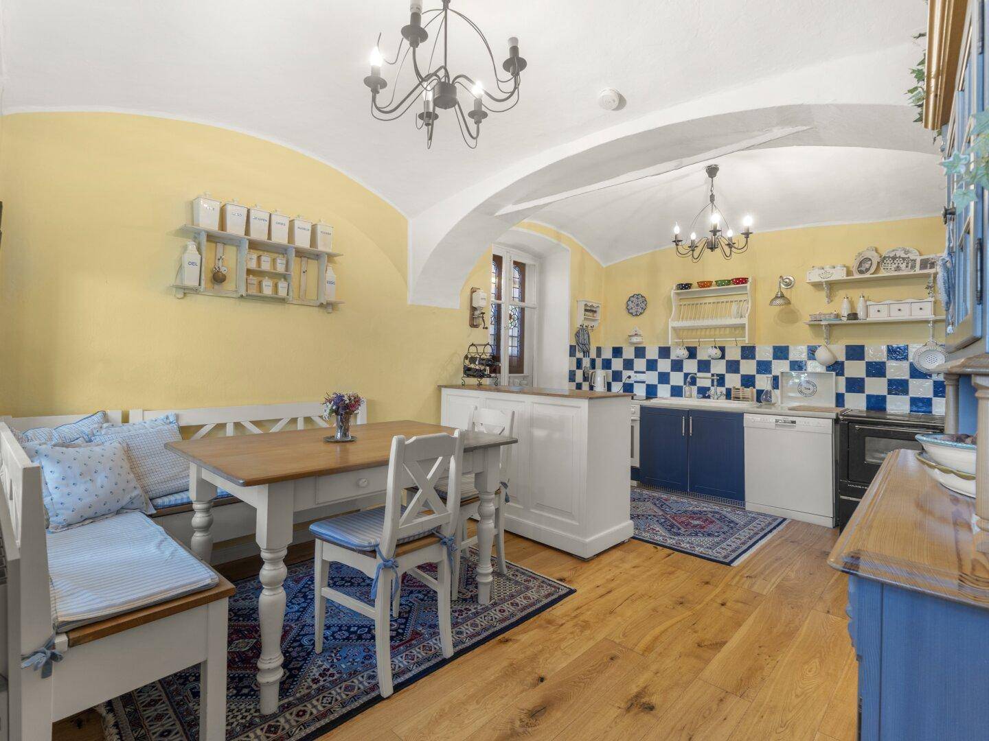 Traditionelle Wohnküche mit gewölbter Decke, blauen Fliesen und Essbereich.