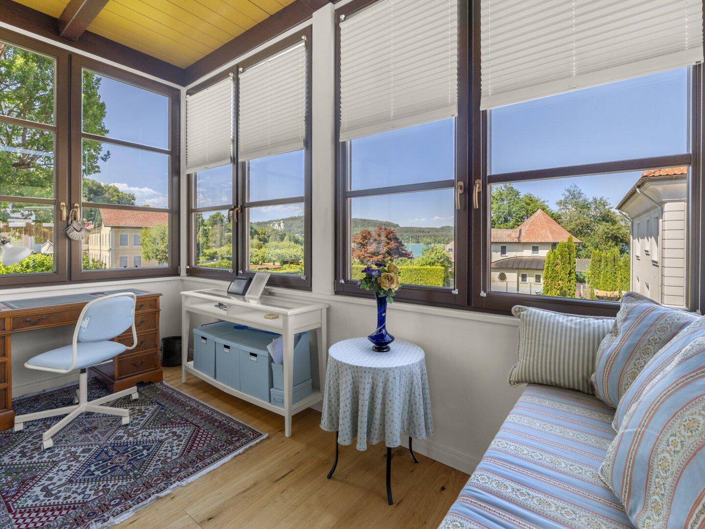 Helles Arbeitszimmer mit Seeblick, großen Fenstern und gemütlicher Sitzecke.