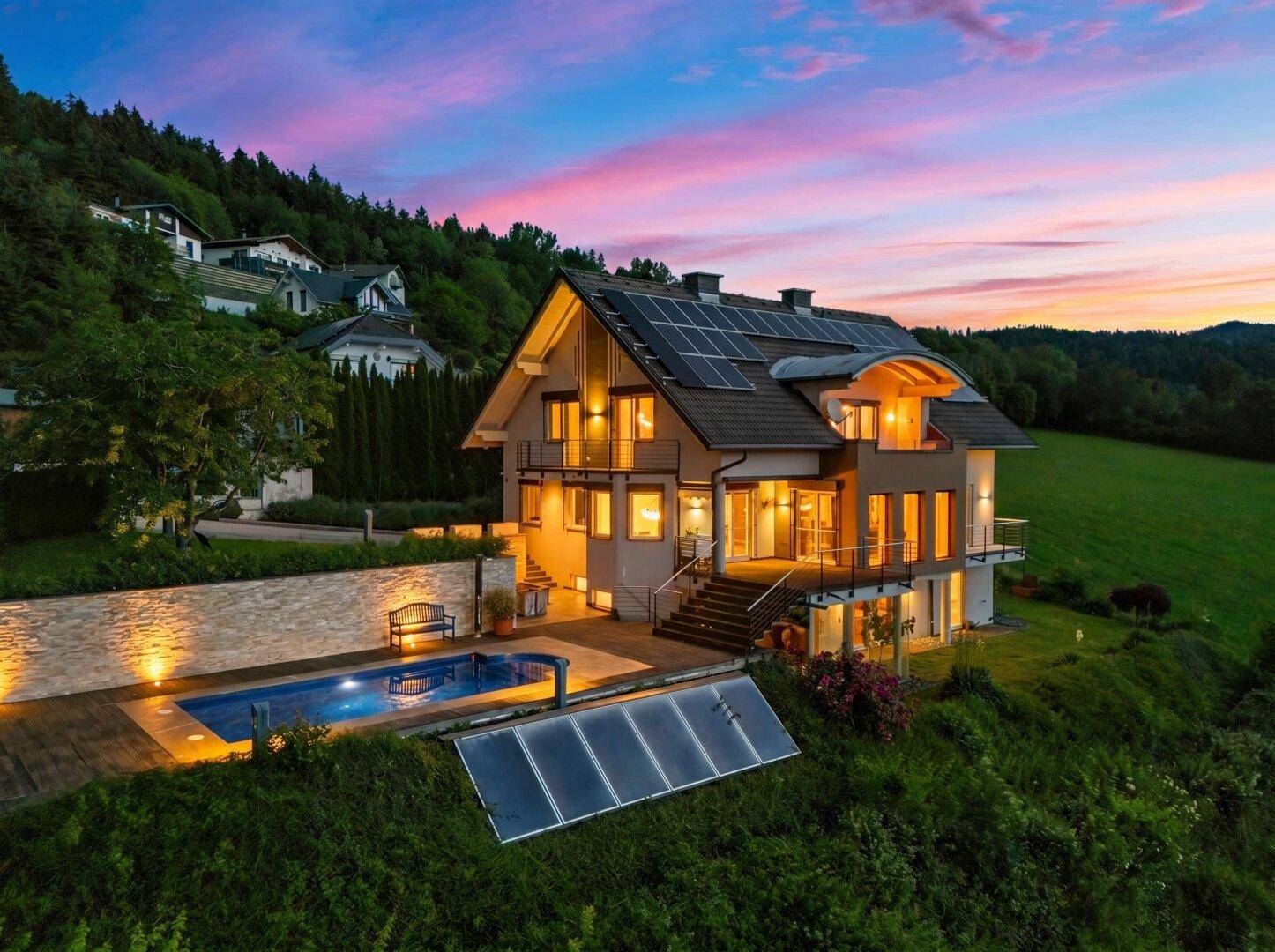 Beeindruckende Luftaufnahme des Hauses mit Pool und Solaranlagen bei farbenprächtigem Sonnenuntergang.