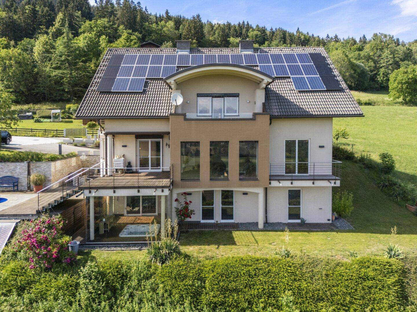 Rückansicht des Hauses mit Solaranlagen auf dem Dach und einem kleinen Poolbereich im Garten.