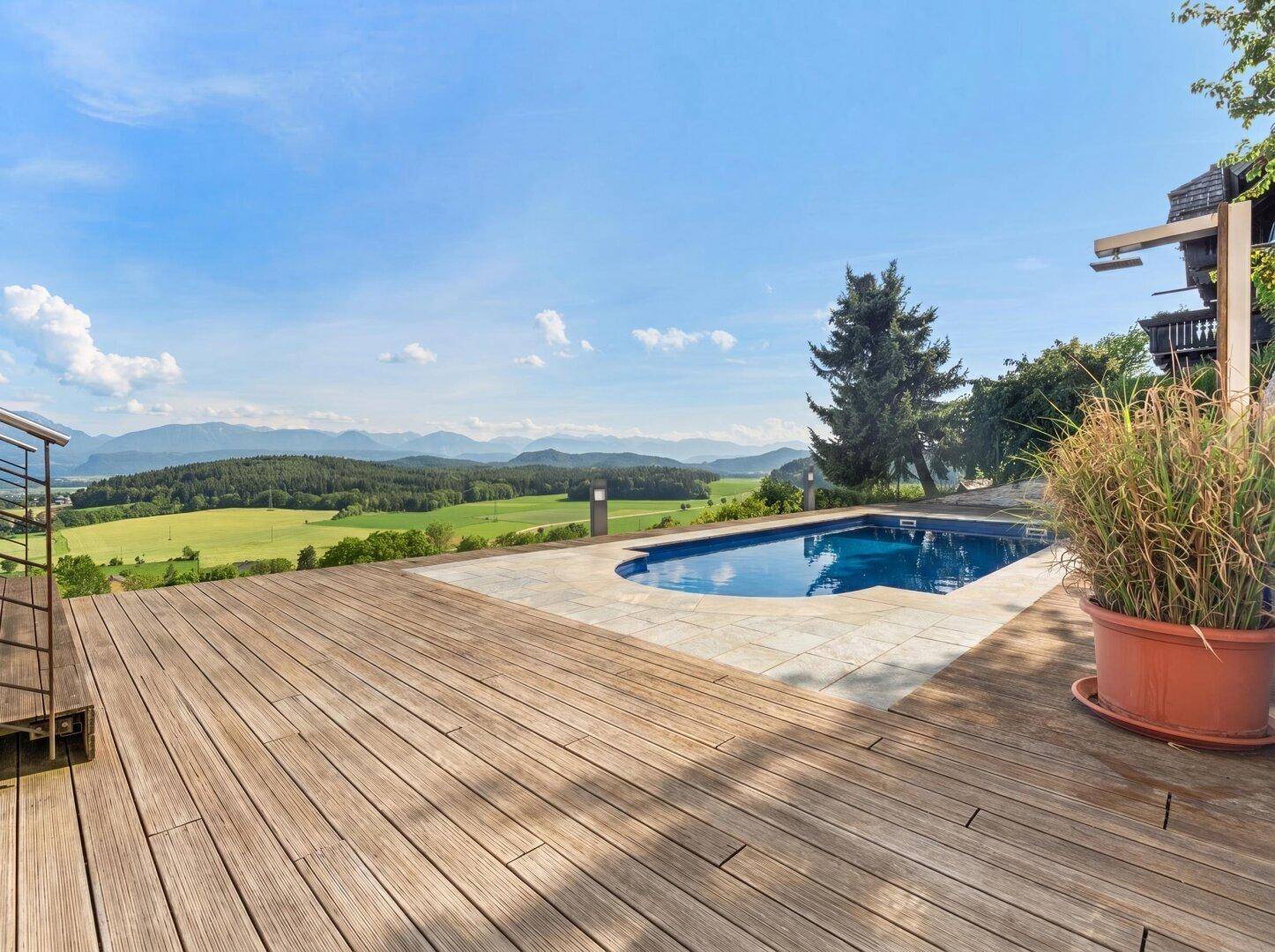 Geräumiges Holzdeck mit Pool und atemberaubendem Panoramablick über die grüne Landschaft und Berge.