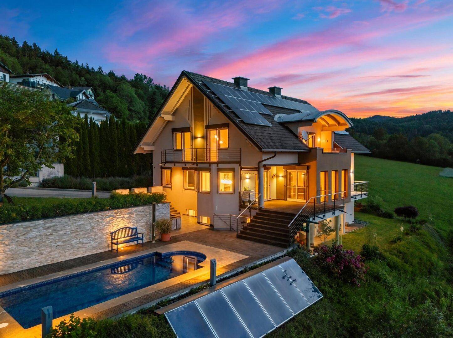 Beeindruckende Luftaufnahme des Hauses mit Pool und Solaranlagen bei farbenprächtigem Sonnenuntergang.