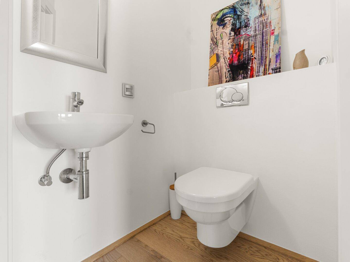 Modernes Gäste-WC mit wandhängender Toilette, kleinem Waschbecken und Holzboden.