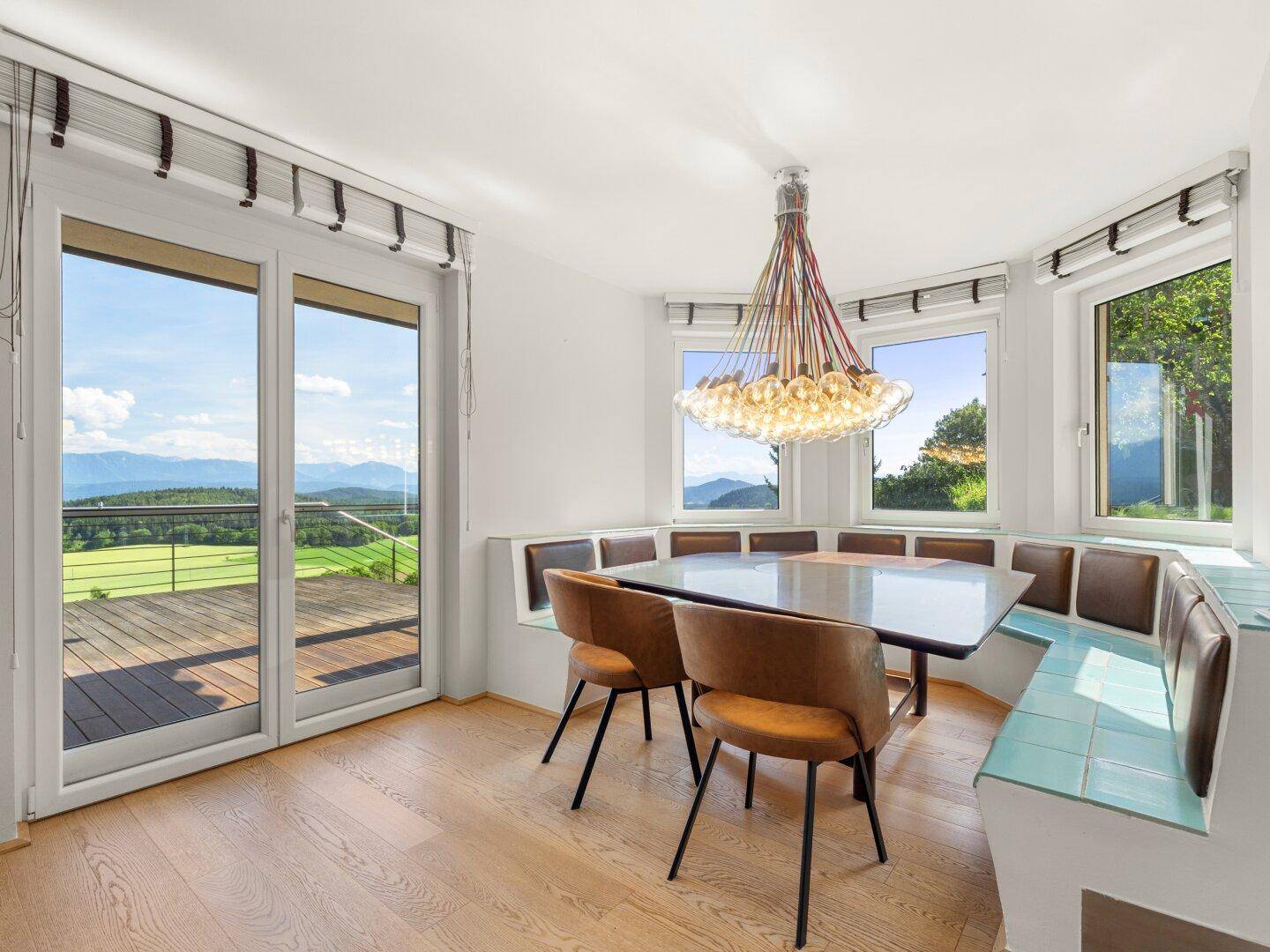 Heller Essbereich mit Holzboden, Eckbank und weitem Bergblick durch große Fenster.