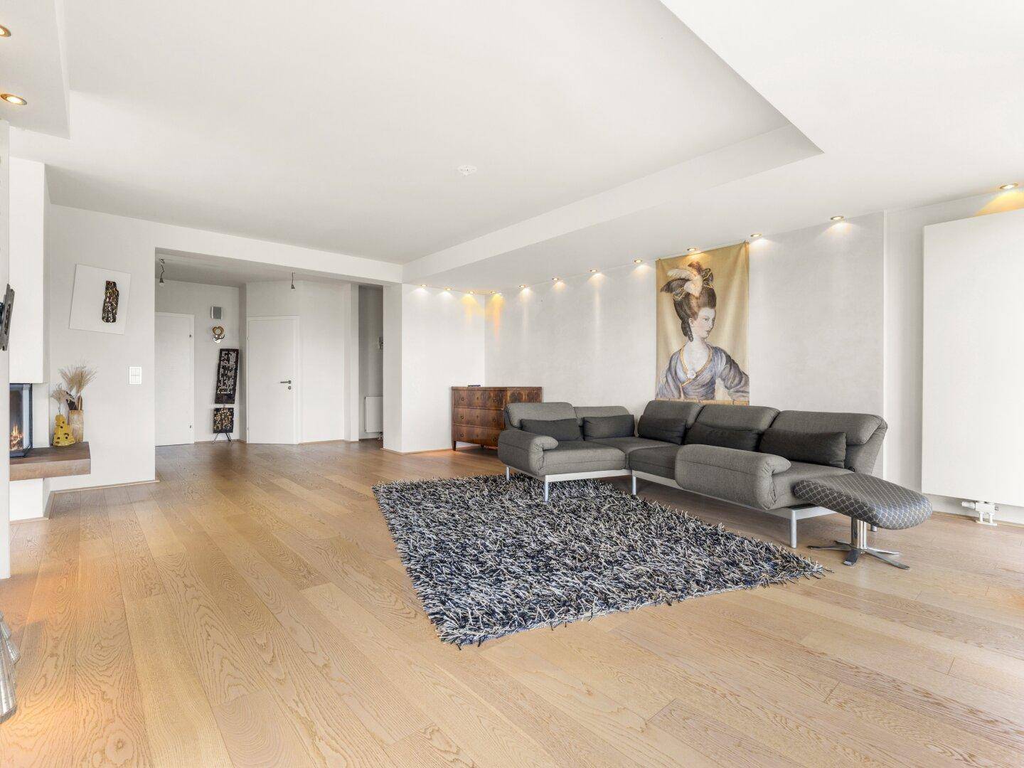 Weitläufiges Wohnzimmer mit modernem Sofa, Teppich und indirekter Beleuchtung.