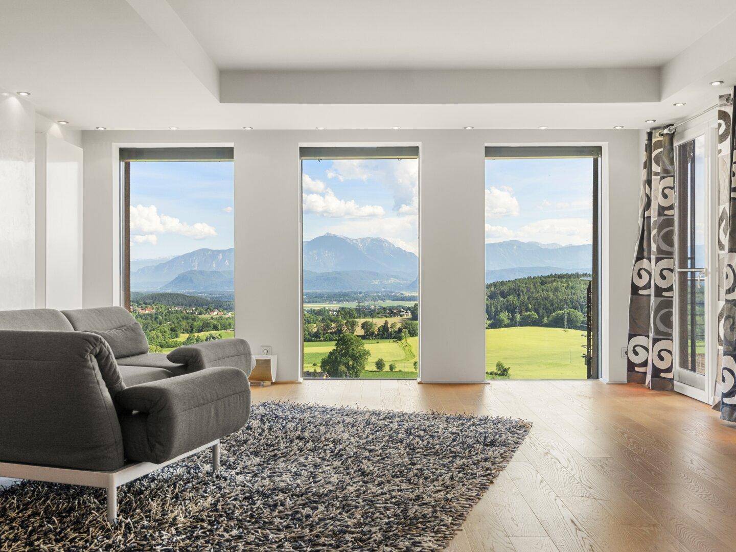 Lichtdurchflutetes Wohnzimmer mit Panoramafenstern und atemberaubendem Berg- und Landschaftsblick.