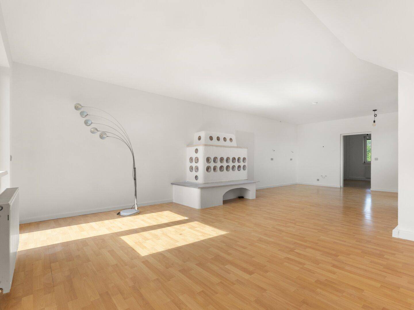 Heller Dachbodenraum mit traditionellem Kachelofen und viel Tageslicht.