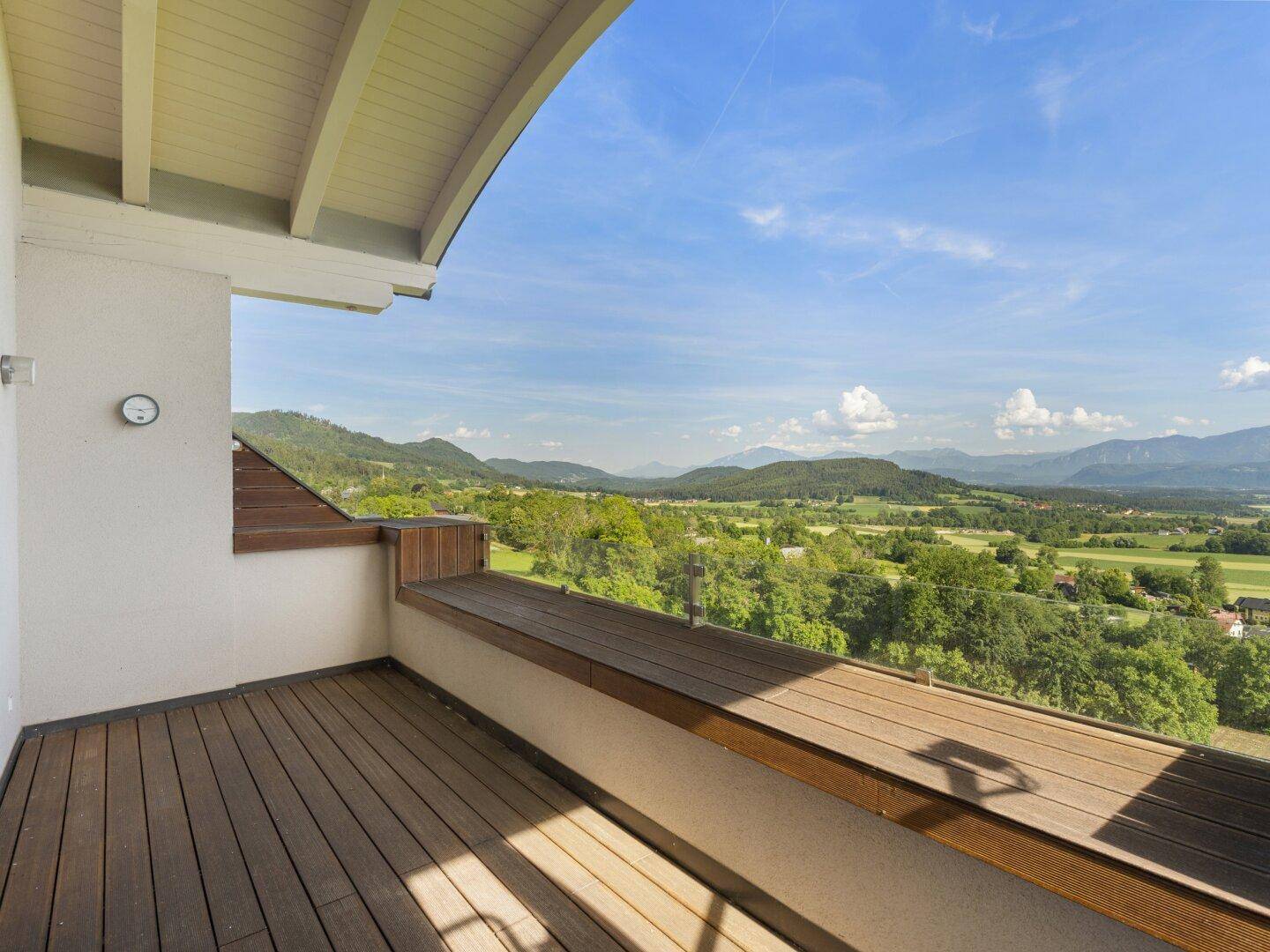 Überdachter Holzbalkon mit integrierter Sitzbank und weitem Blick in die Natur.