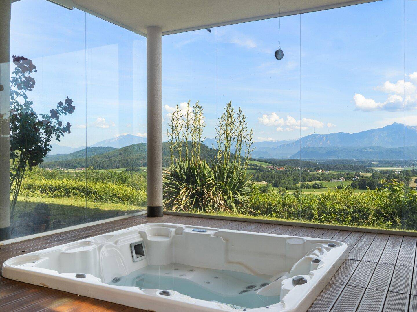 Luxuriöser Whirlpool auf der Holzterrasse mit Glaswänden und Panoramablick.