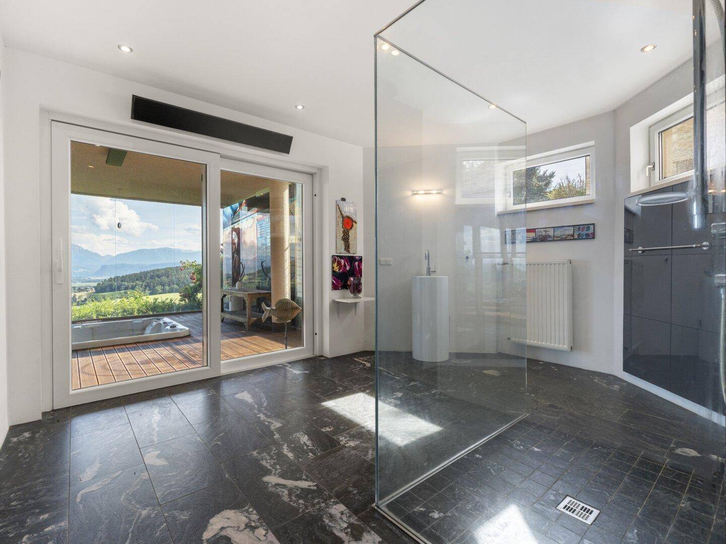 Modernes Badezimmer mit begehbarer Dusche, dunklem Steinboden und Bergblick.