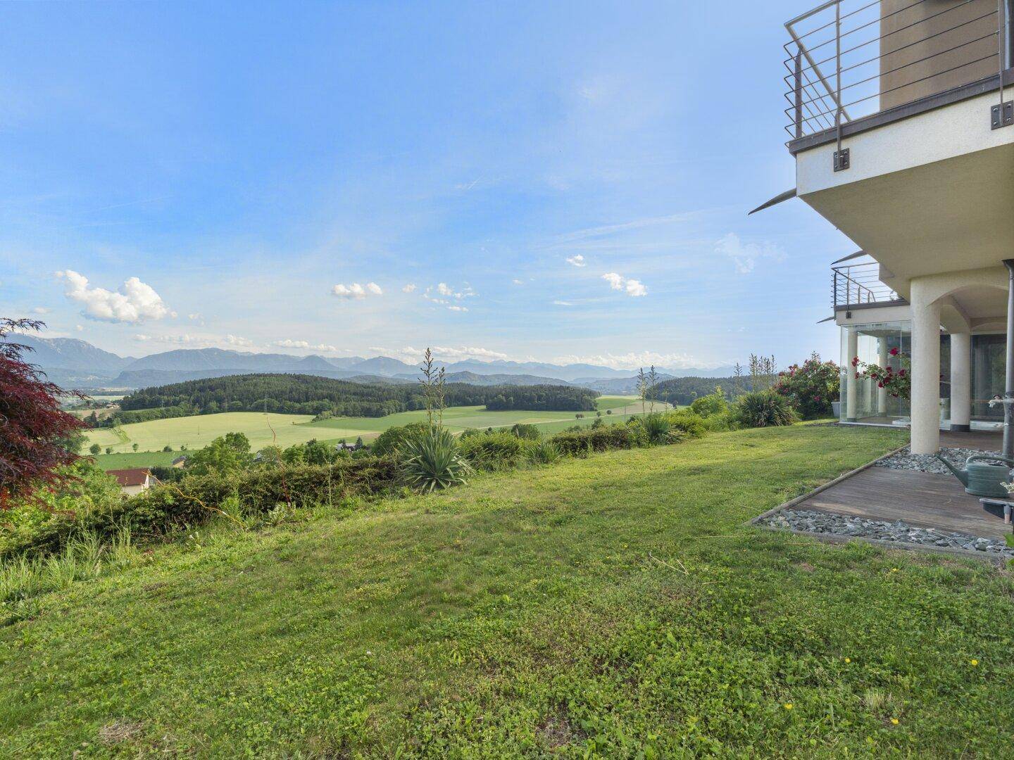 Gepflegter Garten mit Rasenfläche und weitem Blick über die grüne Landschaft und Berge.