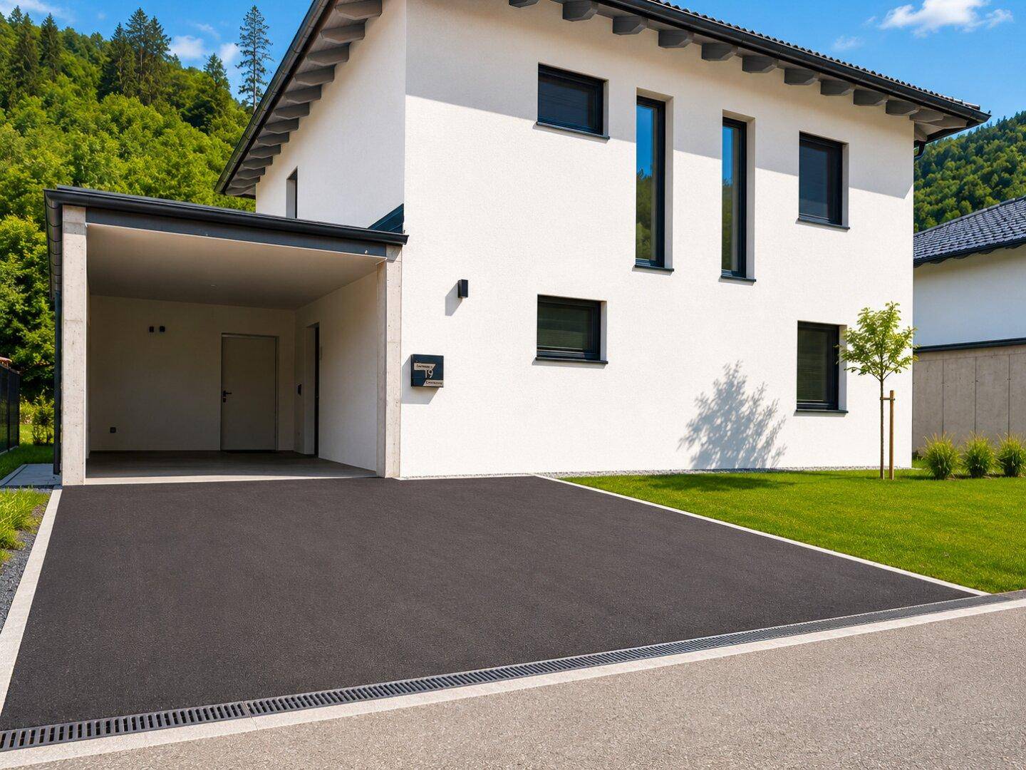 Moderne Hausfassade mit Carport und gepflasterter Auffahrt in sonniger Lage.