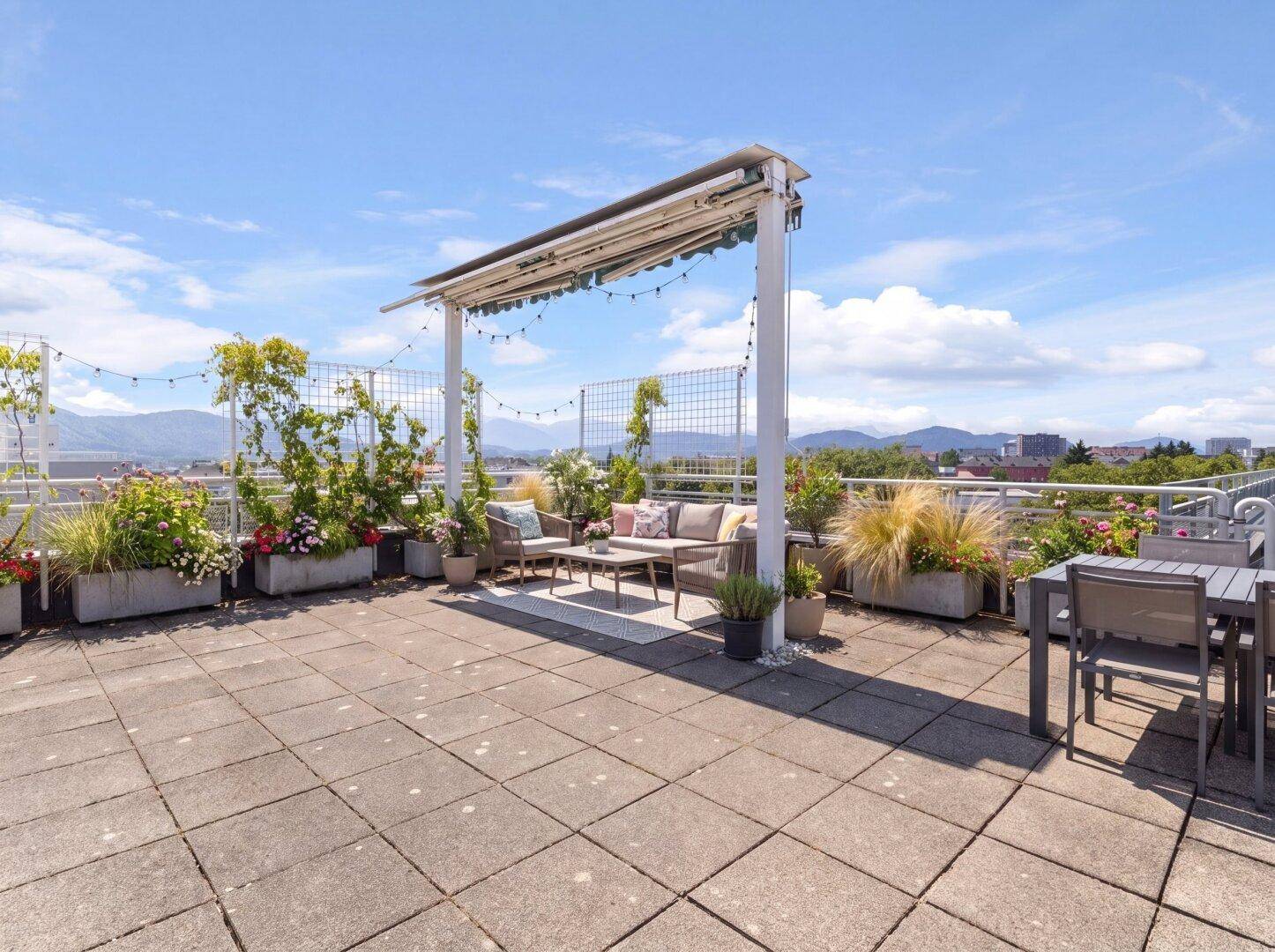 Weitläufige Dachterrasse mit verschiedenen Sitzbereichen, Pflanzen und weitem Blick über die Umgebung.
