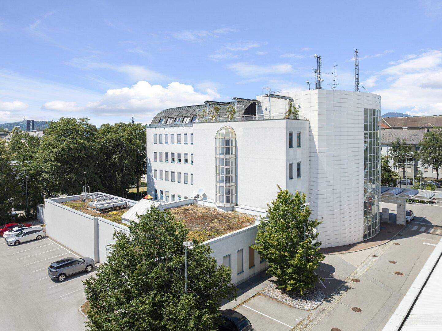 Luftaufnahme des Bürogebäudes mit grünen Dächern, moderner Architektur und umliegenden Parkflächen.