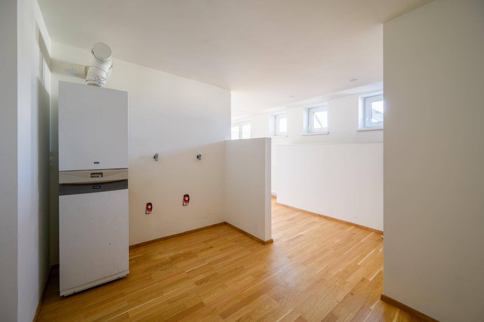 Praktischer Hauswirtschaftsraum mit Heizungsanlage, Anschlüssen und kleinen Fenstern, ideal für Technik und Lagerung.