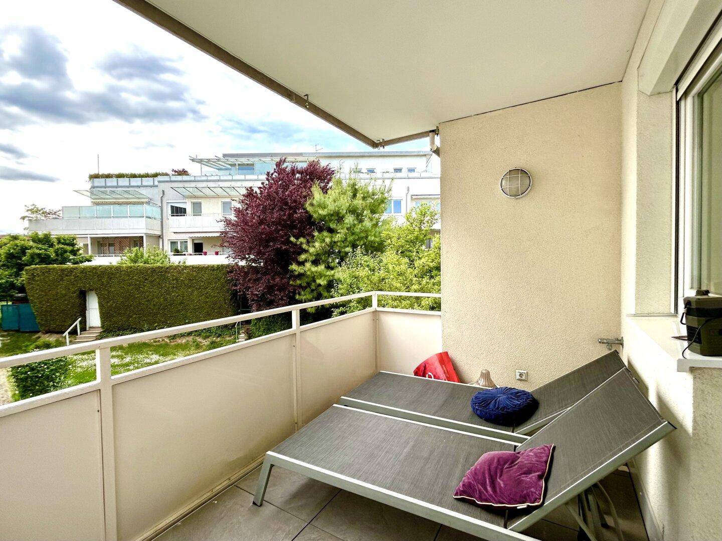 Geräumiger Balkon mit zwei Sonnenliegen und Blick ins Grüne.