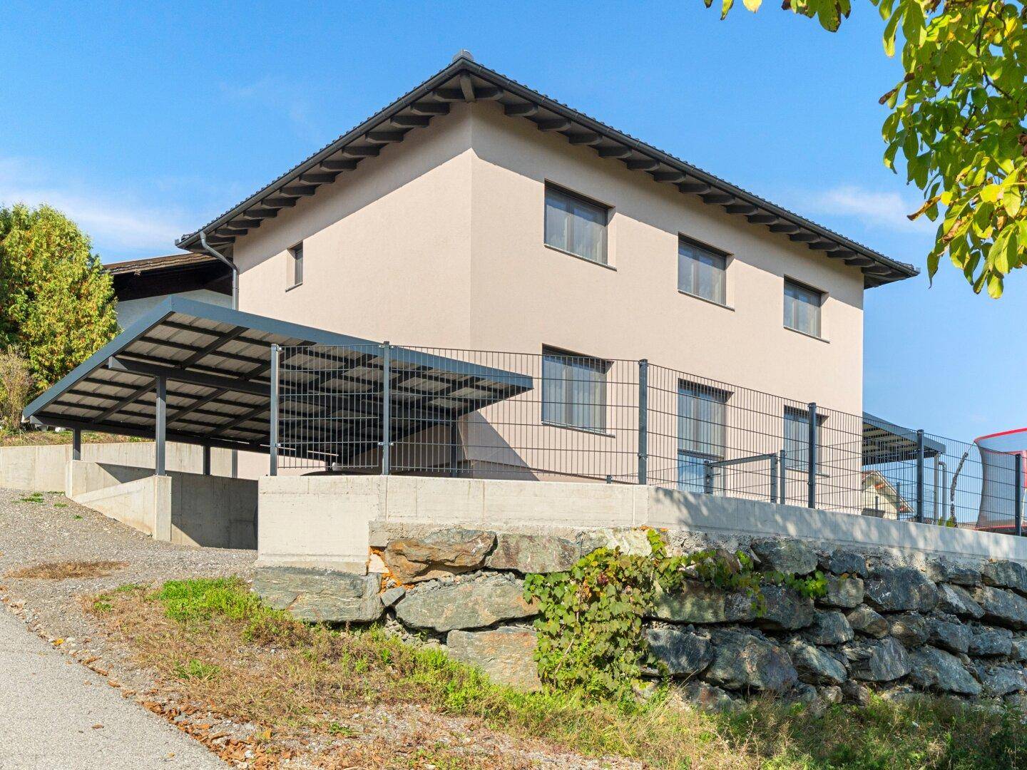 Seitenansicht des modernen Hauses mit Carport und gepflegter Außenanlage.