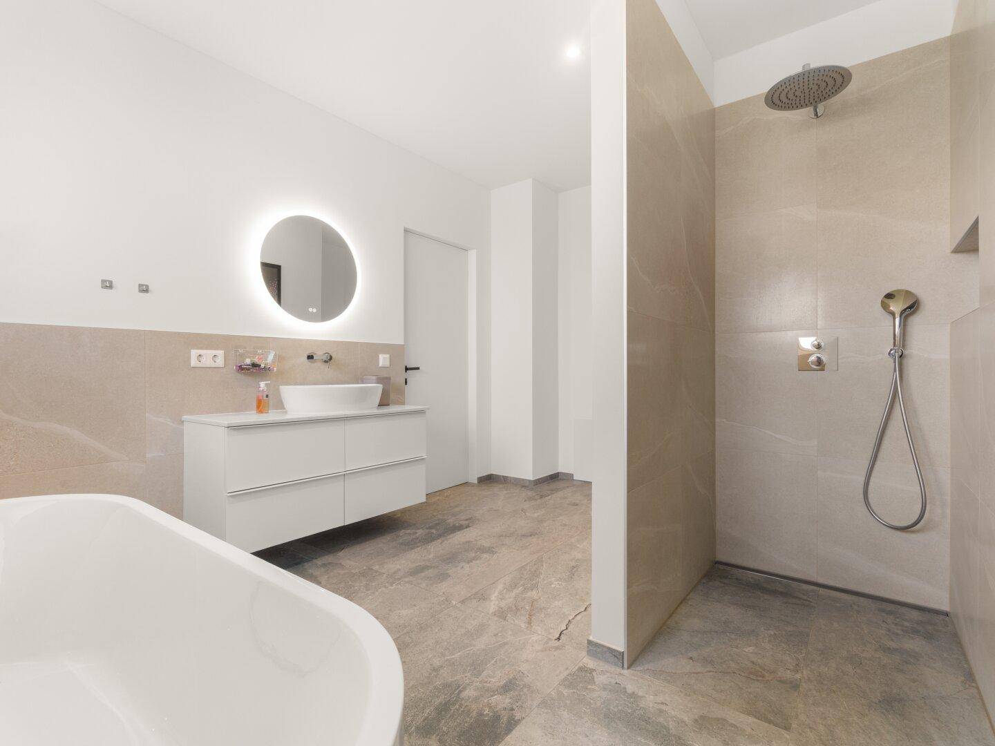 Modernes Badezimmer mit freistehender Badewanne, begehbarer Dusche und eleganten Fliesen.