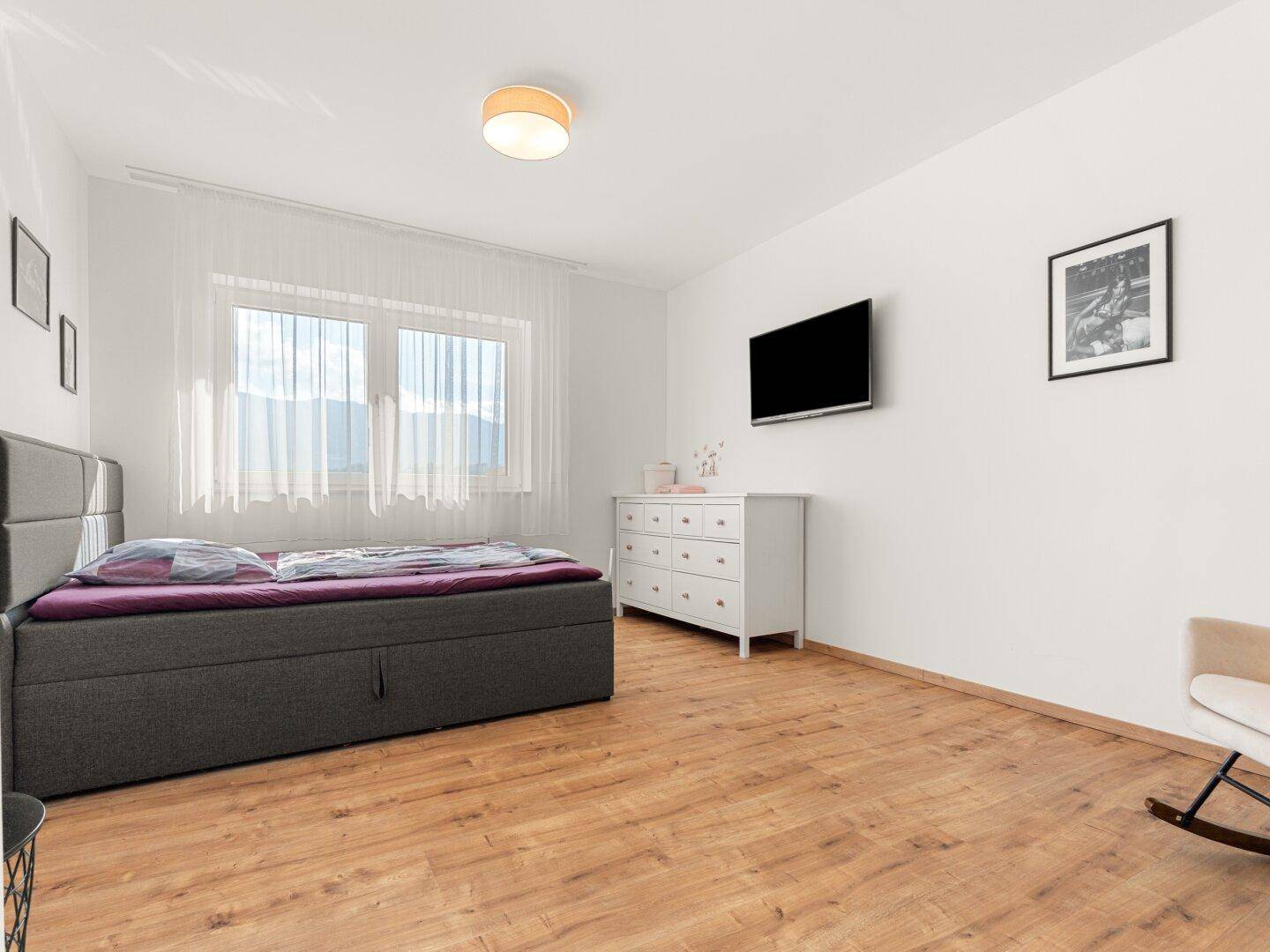 Geräumiges Schlafzimmer mit Doppelbett, Holzboden und Wandfernseher.
