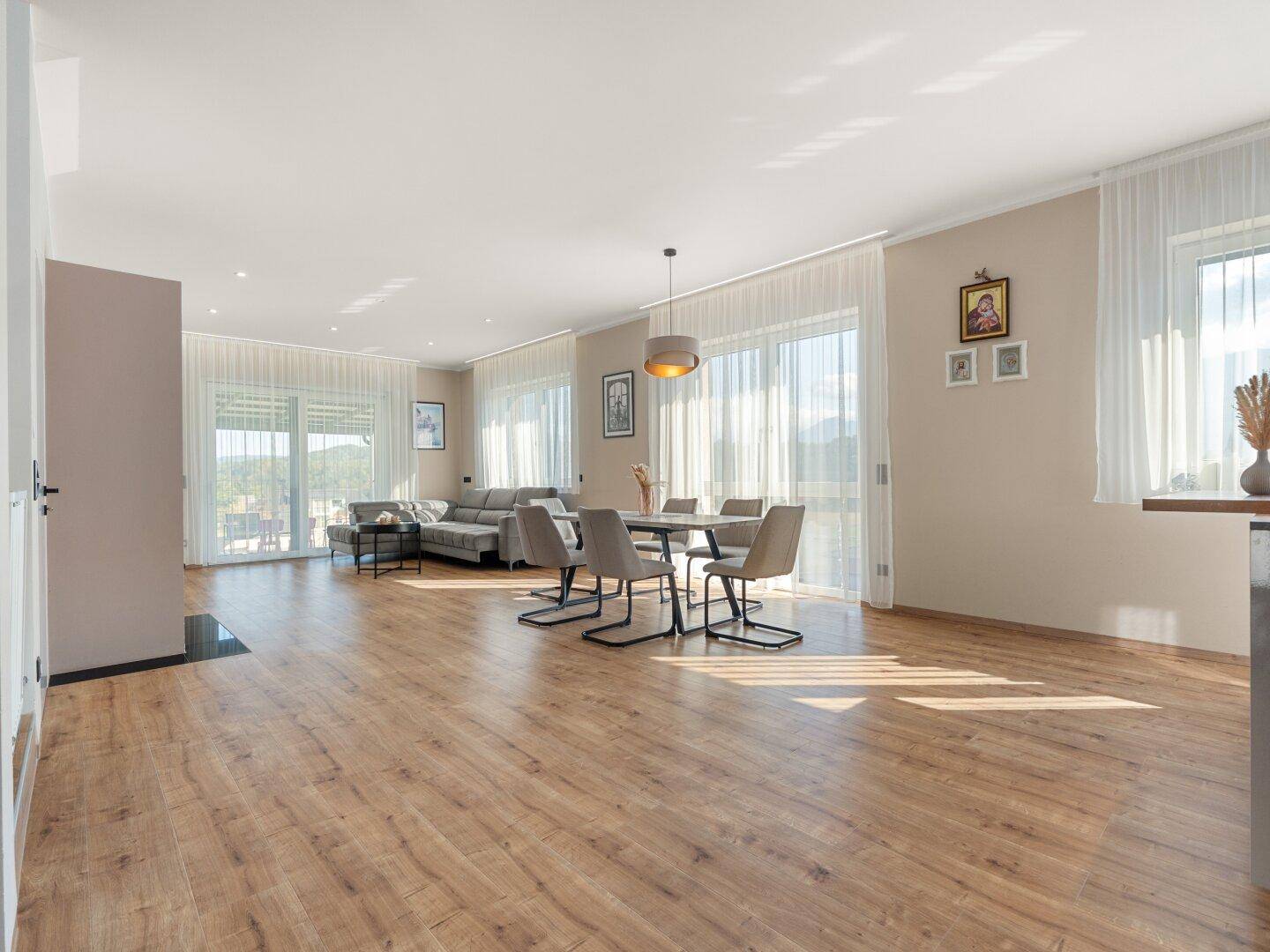 Weitläufiger offener Wohn-Essbereich mit Küche, Kamin und Zugang zur Terrasse.