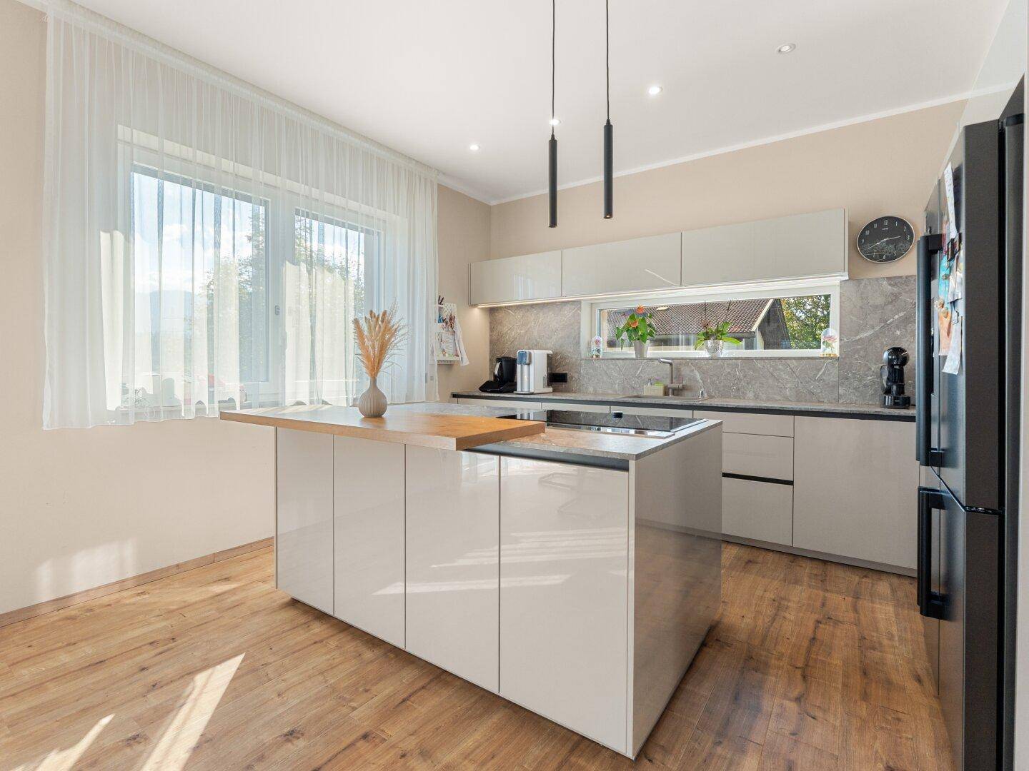 Moderne Küche mit Kücheninsel, Holzarbeitsplatte und großem Fenster.