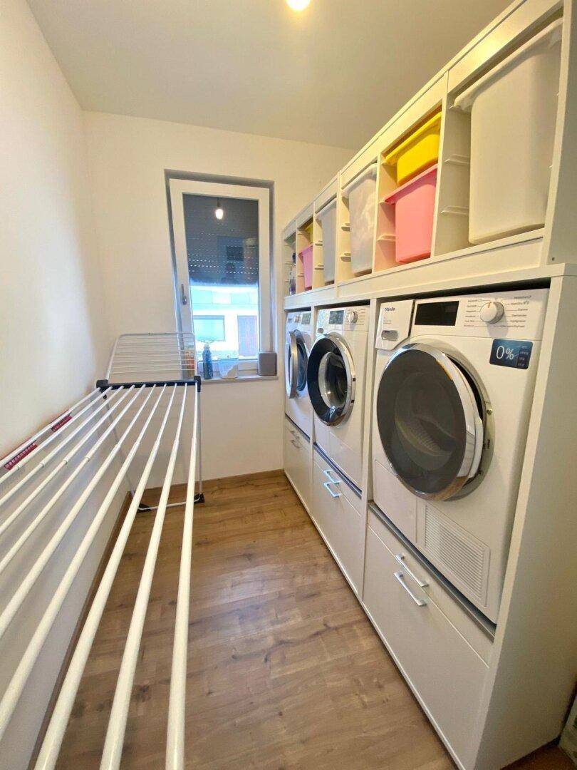 Praktischer Hauswirtschaftsraum mit Waschmaschine, Trockner und Fenster.