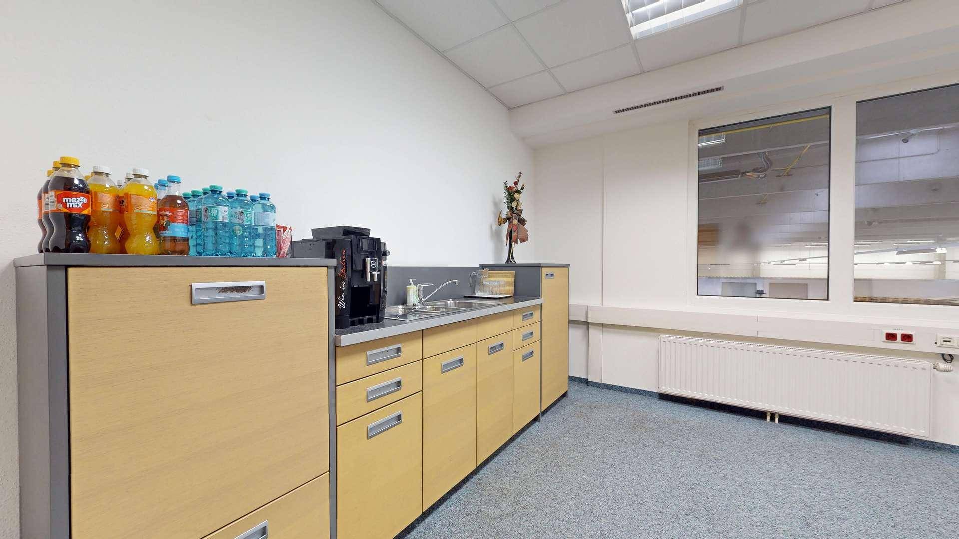 Funktionale Teeküche mit hellen Holzschränken, Spüle und Kaffeemaschine, ideal für Pausen.