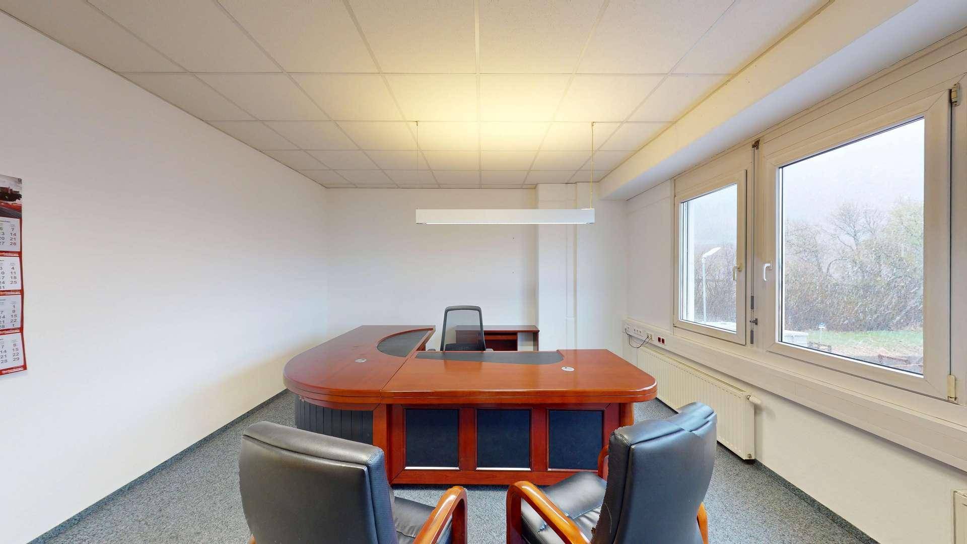 Geräumiges Büro mit einem großen, geschwungenen Holzschreibtisch und bequemen Bürostühlen.