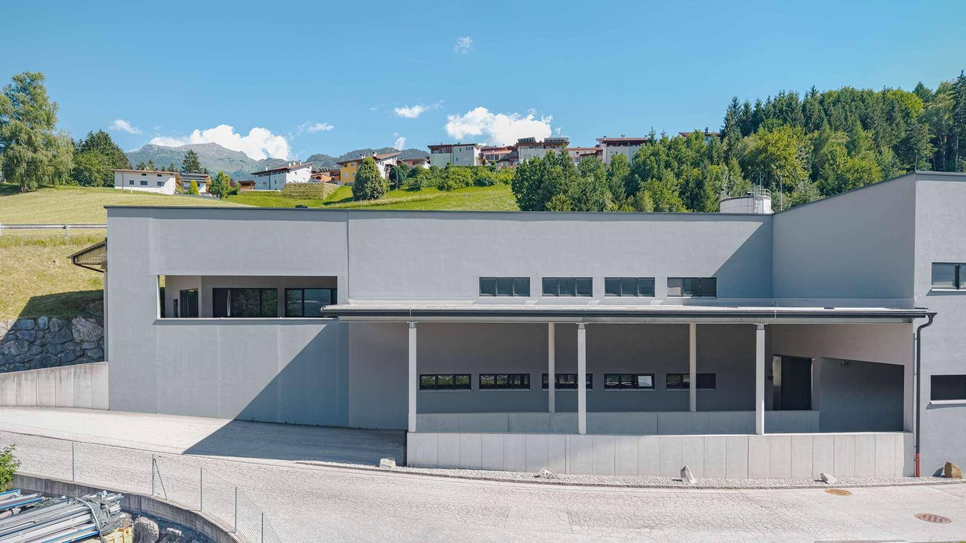 Moderne Gebäudefassade mit horizontalen Fensterbändern und einer überdachten Eingangszone.