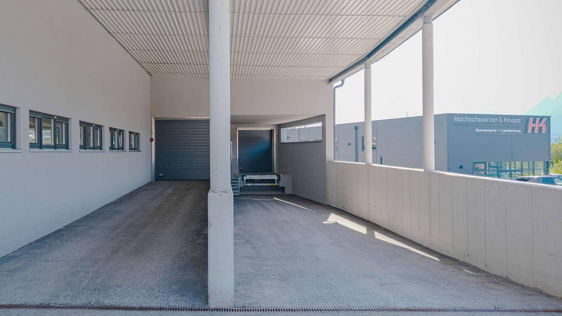 Geräumiger überdachter Bereich mit Zufahrt und Blick auf ein benachbartes Geschäftsgebäude.